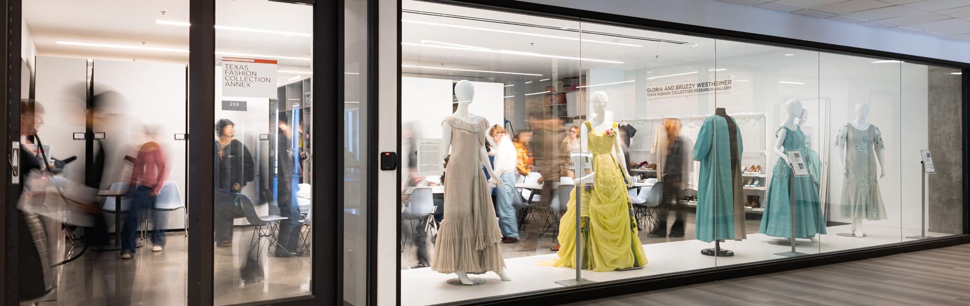 Hallway view of the TFC Gloria and Bruzzy Westheimer Research Gallery with garments on mannequins in the window