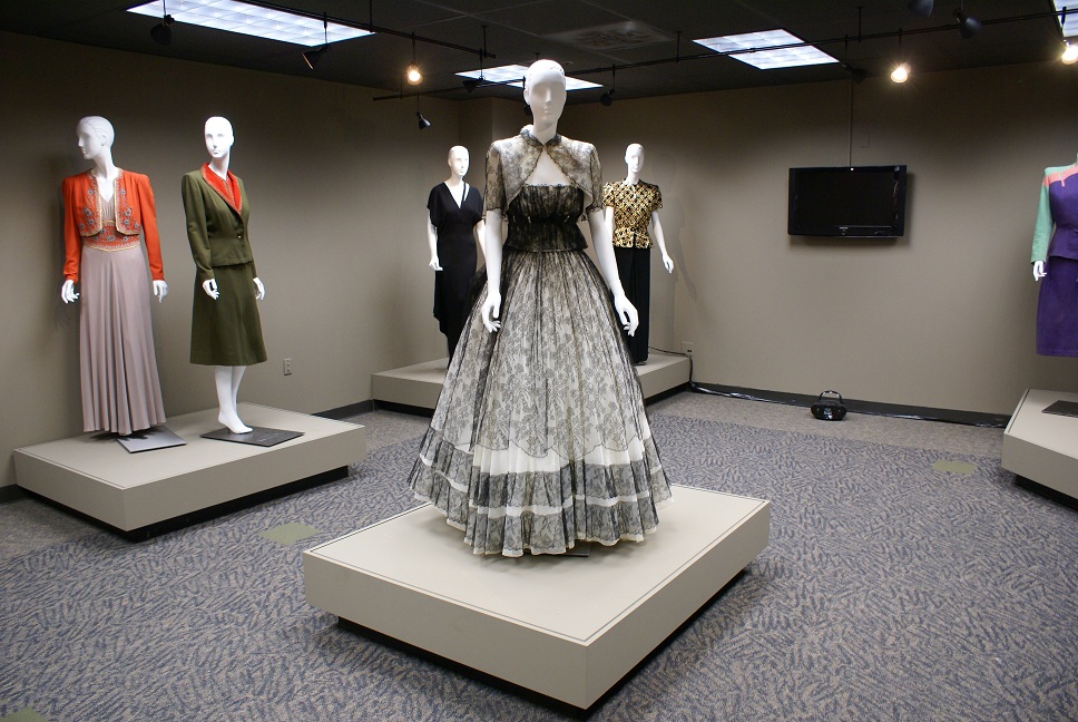 Carpeted gallery with 1940s women's clothing on mannequins on low platforms