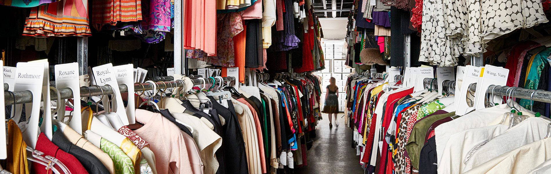 Figure walking down an aisle of clothing in the Texas Fashion Collection storage facility