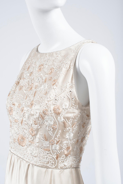 Bodice of off-white silk satin evening dress, featuring white and tan small-scale floral embroidery, shown on a white mannequin